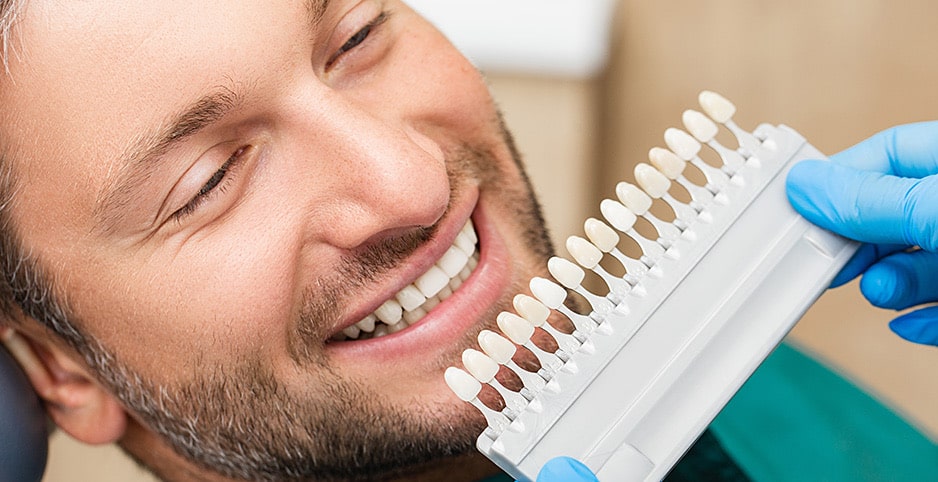 dentist holding shade-matching tool against patient's teeth